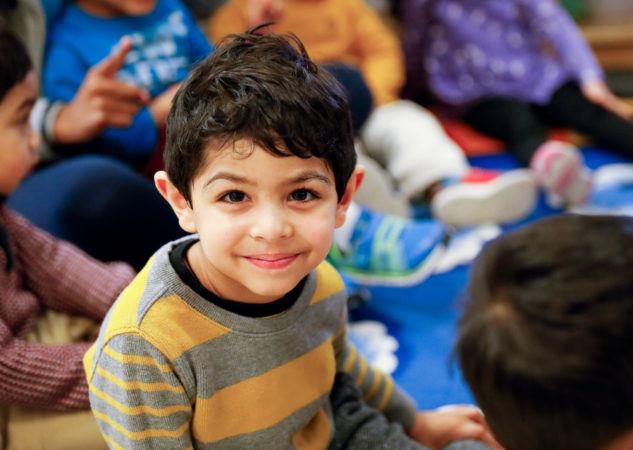 preschool_boy_smiling_at_camera_during_circle_time_winwood_childrens_center_brambleton_va-633x450