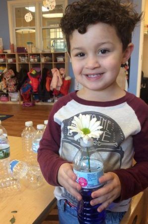 preschool_boy_with_flower_in_water_bottle_cadence_academy_preschool_raynham_ma-298x450