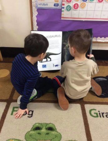 preschool_boys_looking_at_dinosaur_book_cadence_academy_preschool_east_greenwich_ri-347x450