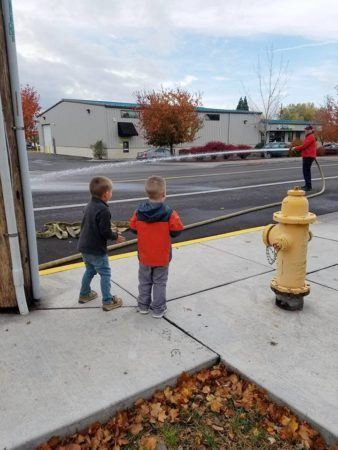 preschool_boys_watching_fireman_using_hose_cadence_academy_preschool_childrens_center_klamath_falls_or-338x450