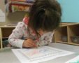 preschool_girl_designing_a_postage_stamp_cadence_academy_preschool_johnston_ia-563x450