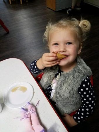 preschool_girl_eating_chicken_nugget_the_bridge_learning_center_carrollton_ga-338x450