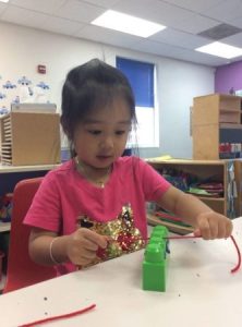 preschool_girl_flossing_plastic_block_growing_kids_academy_fredericksburg_va-333x450