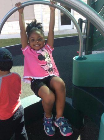 preschool_girl_hanging_from_bar_on_playground_cadence_academy_preschool_austin_cedar_park_tx-336x450