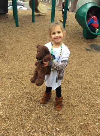 preschool_girl_holding_teddy_bear_on_playground_at_the_peanut_gallery_temple_tx-333x450