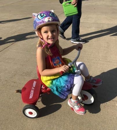 preschool_girl_in_cat_helmet_riding_tricycle_cadence_academy_preschool_main_street_normal_il-405x450