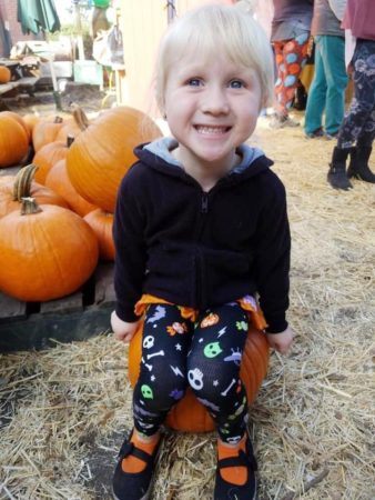 preschool_girl_in_pumpkin_patch_cadence_academy_preschool_wilmington_nc-338x450