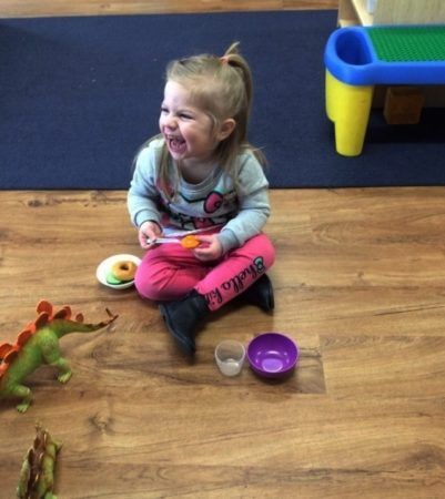 preschool_girl_laughing_while_sitting_cadence_academy_preschool_lincoln_ri-401x450