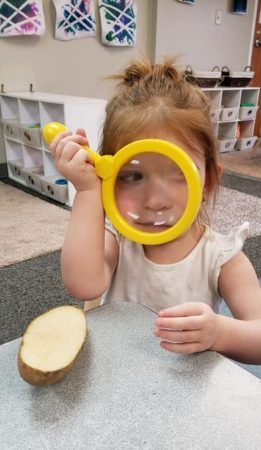 preschool_girl_looking_through_magnifying_glass_jonis_child_care_preschool_canton_ct-261x450