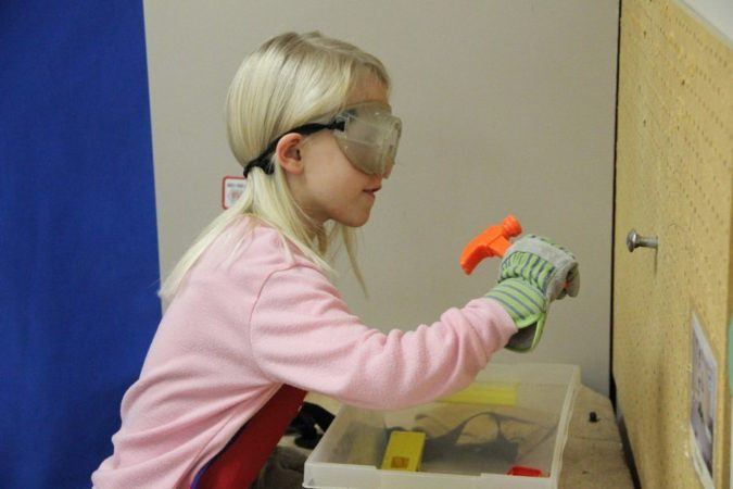 preschool_girl_nailing_screw_into_pegboard_cadence_academy_preschool_clive_ia-675x450