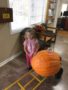 preschool_girl_next_to_giant_pumpkin_miss_muffets_learning_center_klamath_falls_or-338x450