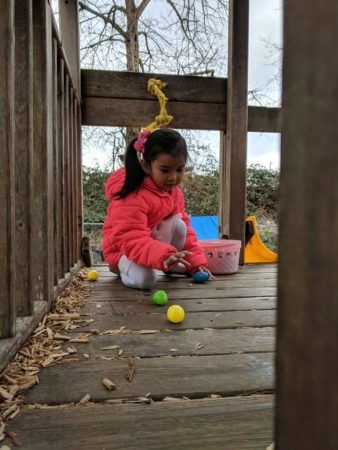 preschool_girl_picking_up_easter_eggs_on_playground_cadence_academy_preschool_tacoma_wa-338x450