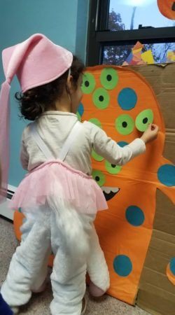 preschool_girl_putting_eye_on_monster_at_cadence_academy_preschool_norwood_ma-250x450