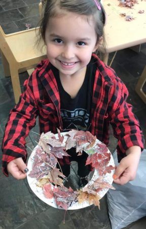 preschool_girl_showing_off_her_leaf_wreath_cadence_academy_preschool_childrens_center_klamath_falls_or-288x450