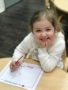 preschool_girl_smiling_and_thinking_of_what_to_write_sunbrook_academy_at_legacy_park_kennesaw_ga-338x450