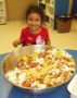 preschool_girl_smiling_in_front_of_snack_mix_cadence_academy_preschool_carmichael_ca-357x450