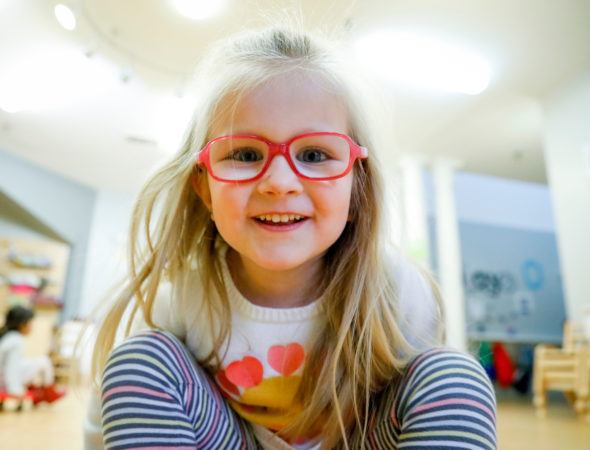 preschool_girl_smiling_into_camera_at_winwood_childrens_center_brambleton_va-590x450