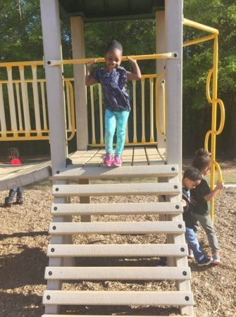 preschool_girl_smiling_on_playground_equipment_sunbrook_academy_at_chapel_hill_douglasville_ga-335x450