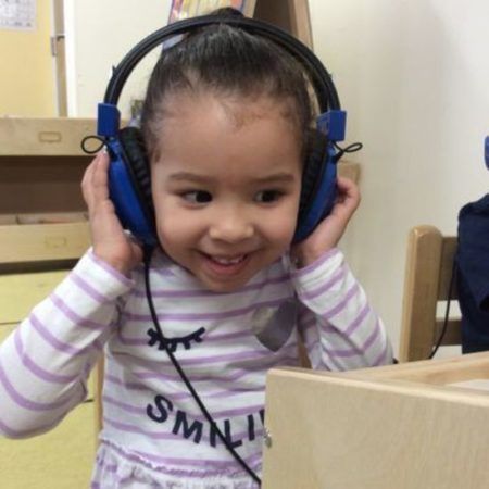 preschool_girl_smiling_while_on_headphones_cadence_academy_preschool_west_bridgewater_ma-450x450