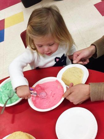 preschool_girl_spooning_out_food_at_cadence_academy_preschool_ken_caryl_littleton_co-338x450