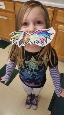 preschool_girl_wearing_multi-colored_mustache_learning_edge_childcare_and_preschool_oak_creek_wi-253x450