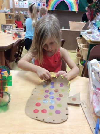 preschool_girl_weaving_a_cardboard_pumpkin_creative_expressions_learning_center_eureka_mo-336x450