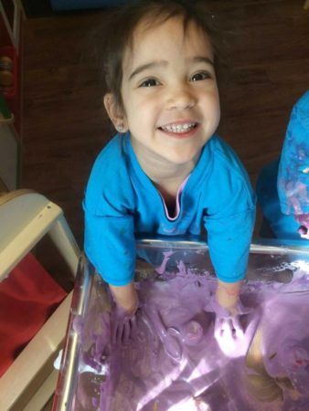 preschool_girl_with_hands_in_purple_goop_cadence_academy_preschool_raynham_ma-338x450