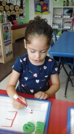 preschool_girl_writing_the_letter_e_prime_time_early_learning_centers_edgewater_nj-248x450