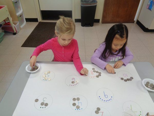 preschool_girls_counting_with_quarters_cadence_academy_preschool_clive_ia-600x450