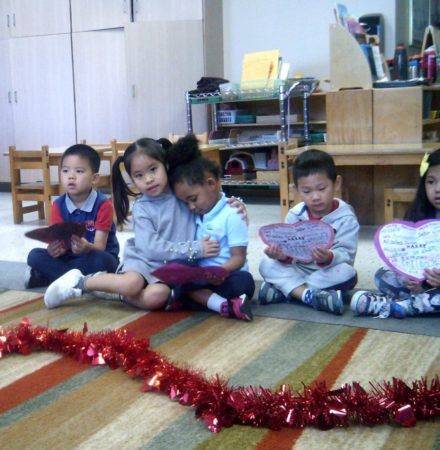 preschool_girls_hugging_during_valentines_day_smaller_scholars_montessori_academy_grisby_tx-440x450