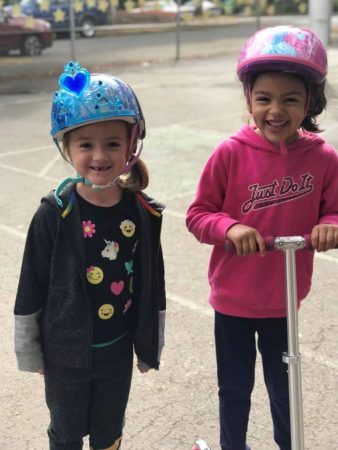 preschool_girls_riding_scooters_with_helmets_cadence_academy_preschool_sellwood_portland_or-338x450