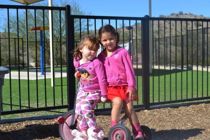 preschool_girls_sitting_on_tricycle_at_phoenix_childrens_academy_private_preschool_estrella_mountain_az-675x450