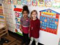 preschool_girls_standing_next_to_calendar_cadence_academy_preschool_east_greenwich_ri-599x450