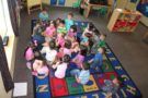 preschool_teacher_and_class_sitting_on_ground_cadence_academy_preschool_san_antonio_tx-675x450