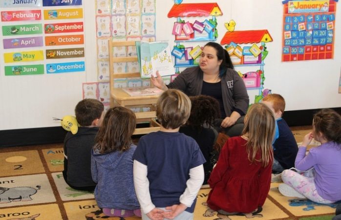 preschool_teacher_reading_to_students_cadence_academy_preschool_east_greenwich_ri-698x450