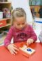 preschooler_doing_peg_activity_cadence_academy_preschool_wilmington_nc-311x450