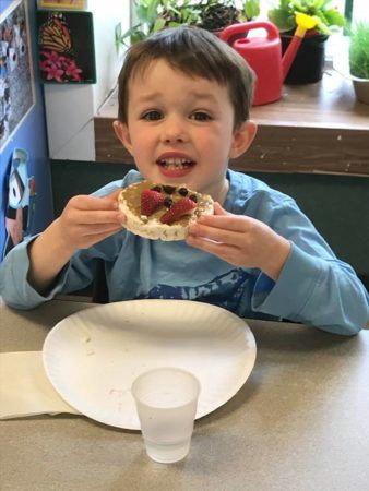 preschooler_eating_healthy_rice_cake_and_fruit_winwood_childrens_center_reston_va-338x450