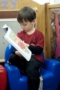 preschooler_reading_book_on_a_soft_chair_cadence_academy_preschool_greensboro_nc-300x450