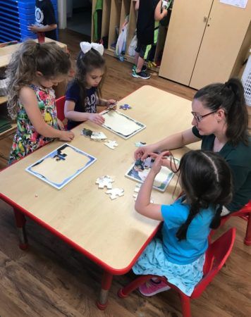 preschoolers_and_teacher_working_on_puzzles_cadence_academy_preschool_smithfield_ri-356x450