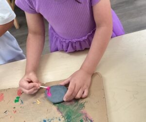 young child painting rock with a cotton swab at cadence academy preschool and daycare in dupont washington