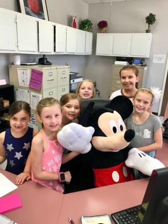 school_age_students_and_mickie_at_front_desk_at_superman_preschooler_cadence_academy_preschool_rocklin_ca-338x450