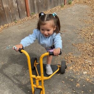 child riding a scooter outside in cadence academy preschool and daycare in dupont washington
