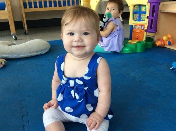 smiling_toddler_sitting_on_padded_blue_floor_cadence_academy_preschool_greenville_sc-605x450