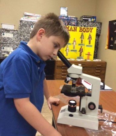 student_looking_through_microscope_cadence_academy_academy_cordova_tn-384x450