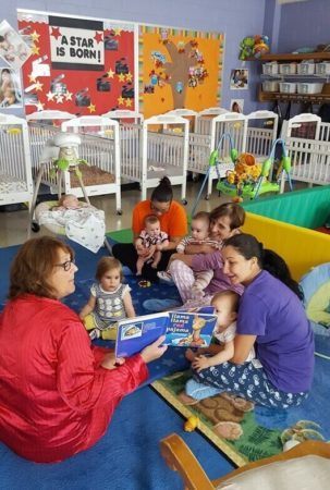 teachers_cuddling_and_reading_to_infants_prime_time_early_learning_centers_east_rutherford_nj-303x450