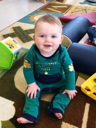 toddler_boy_smiling_and_sitting_on_rug_cadence_academy_preschool_mount_pleasant_sc-338x450