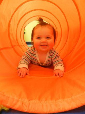 toddler_crawling_through_orange_tunnel_creative_kids_childcare_centers_kent-338x450
