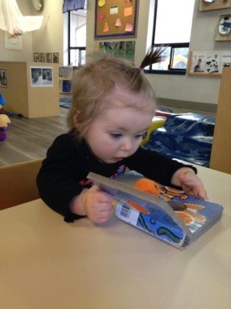 toddler_girl_amazed_by_fish_book_cadence_academy_preschool_tacoma_wa-336x450