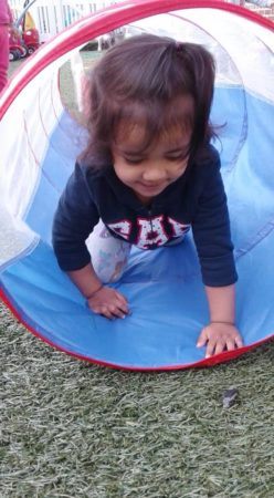 toddler_girl_crawling_through_tunnel_on_the_playground_prime_time_early_learning_centers_edgewater_nj-248x450
