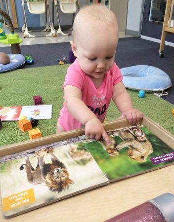 toddler_looking_at_baboon_book_cadence_academy_preschool_gig_harbor_wa-352x450